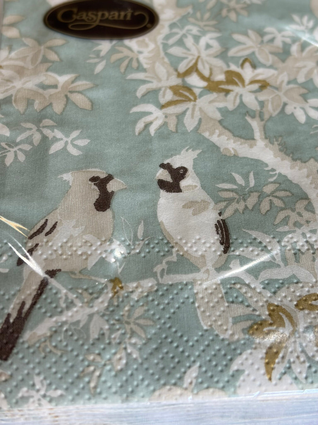 Detalle del estampado: dos aves blancas posadas en una rama entre hojas doradas