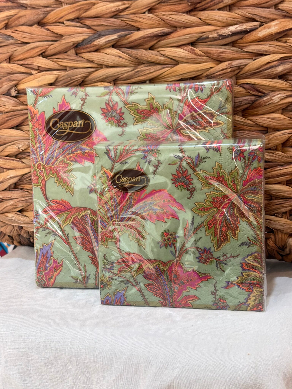 Servilletas de papel con estampado floral en rosas y rojos sobre fondo verde salvia, los dos formatos