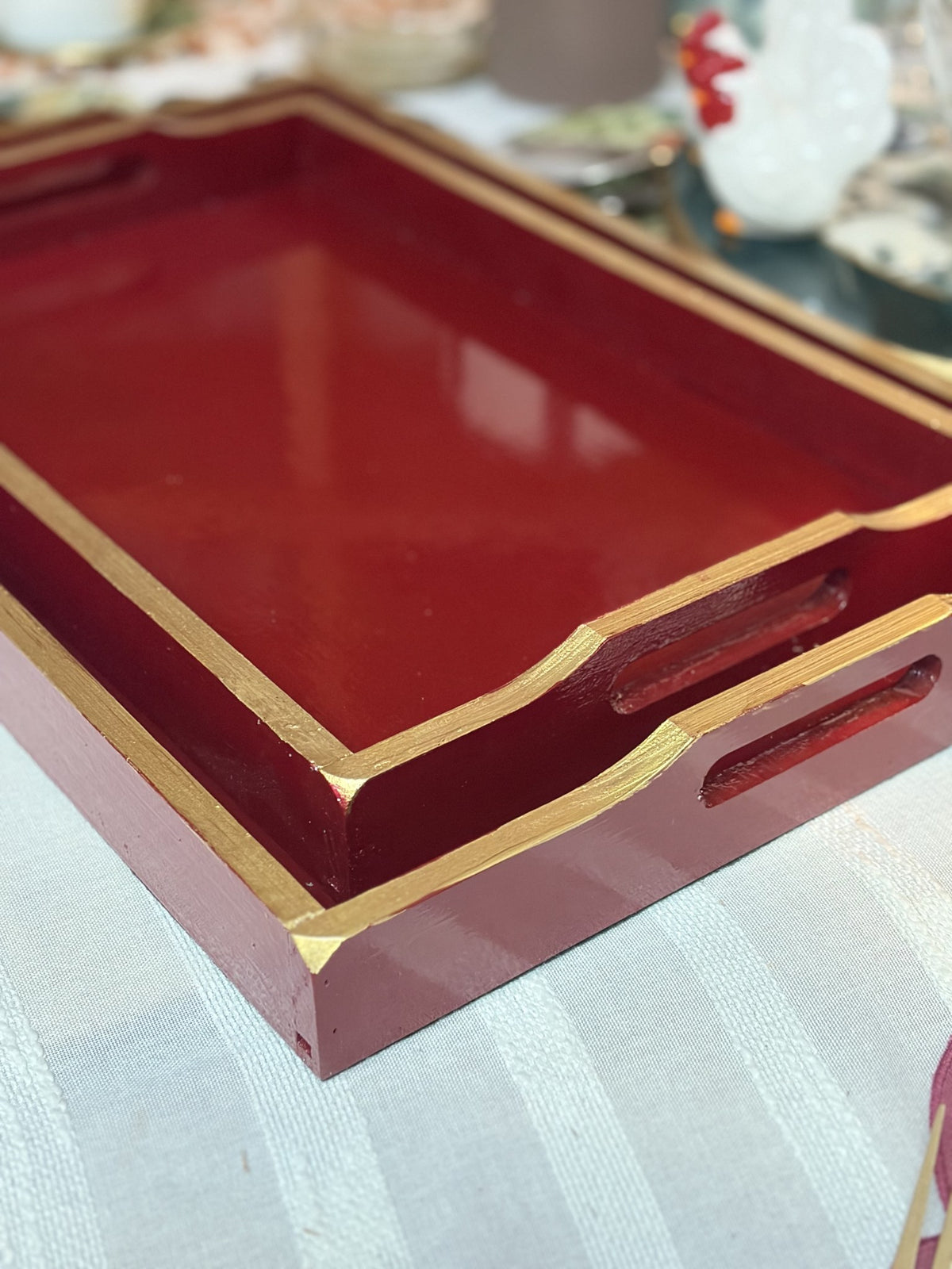 Detalle del borde dorado y las asas de la bandeja granate