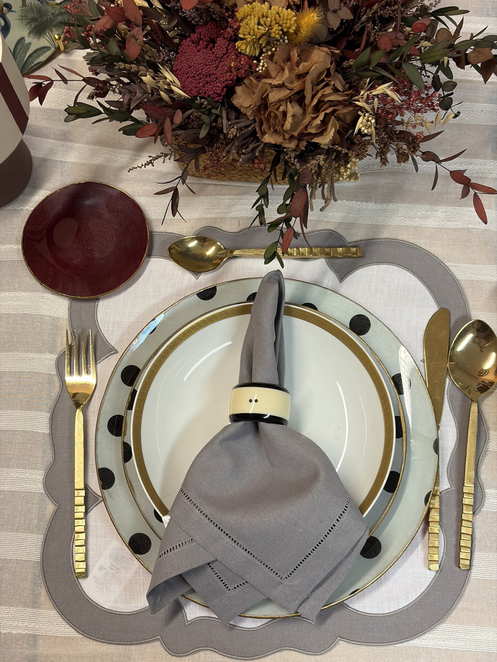 Mesa puesta con servilleta gris, mantel individual gris y vajilla de lunares
