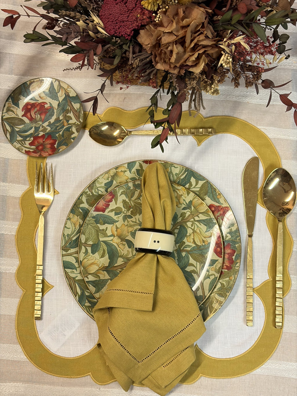 Mesa puesta con servilleta mostaza, mantel individual mostaza y plato floral