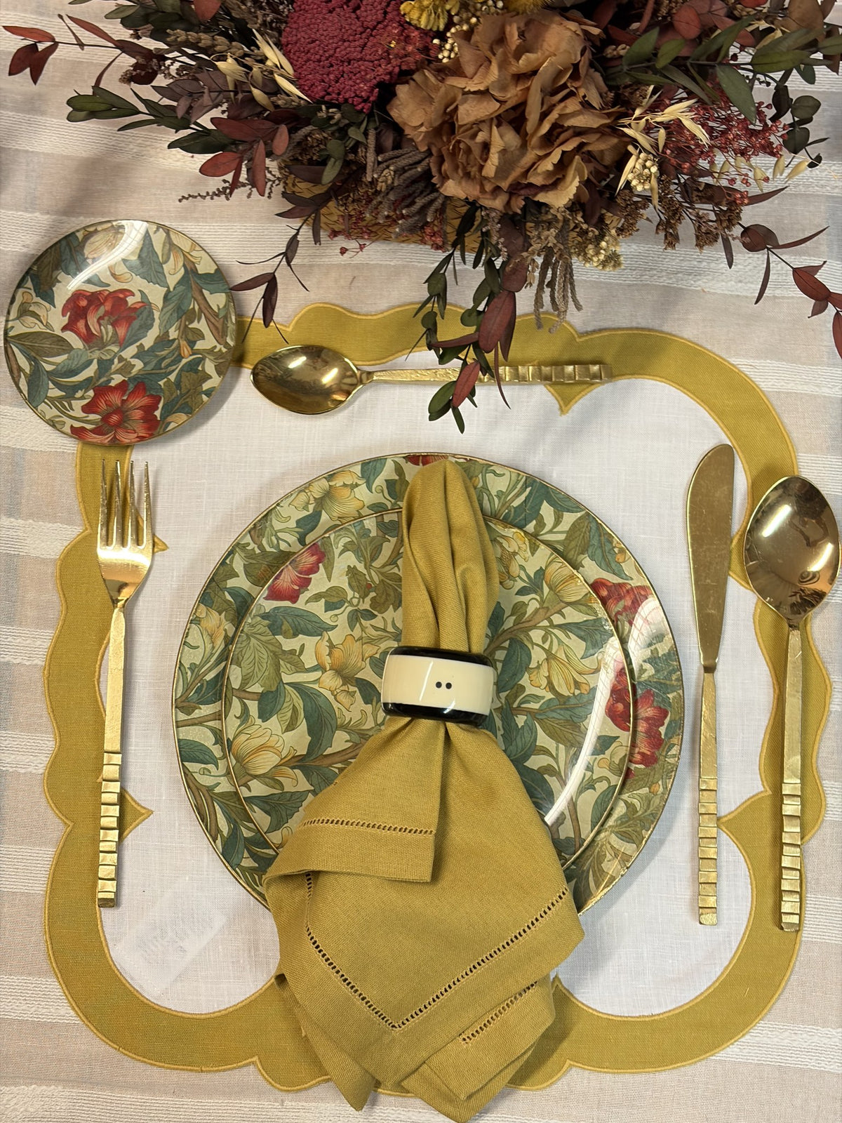 Mesa puesta con servilleta mostaza, mantel individual mostaza y plato floral